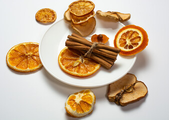dried orange and cinnamon slices on a white plate. white table background. holiday concept, table decoration, meeting new year and christmas.