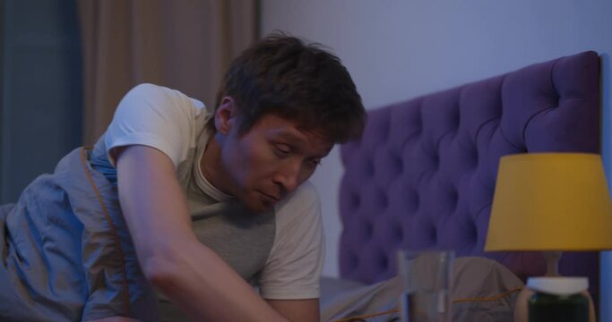 Man lying in bed taking sleeping pill or night medicine