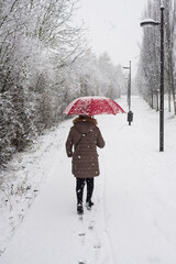 Portrait on back view of woman walking with a red umbrella by snowy day