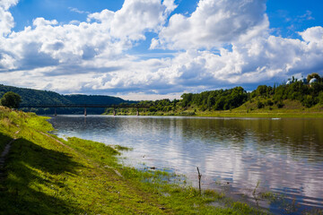 Beautiful view over the river Dniester and its riverbank on a sunny summer's day with background of bridge against the of hills. Outdoor recreation. Swimming, summer vacation, outdoor activities.