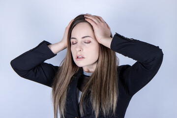 An attractive business woman or student wearing a business suit looking stressed and upset with her hands on her head as if she has a headache