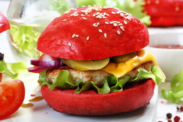 Burger with red bun and chicken cutlet on white plate