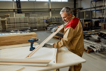 Woodworker checking frame piece while working at carpentry workshop.