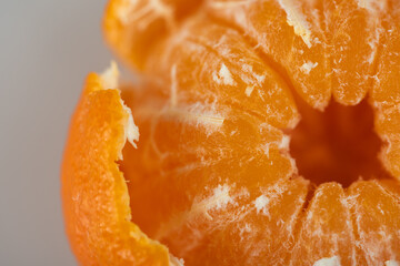 Fototapeta na wymiar juicy sweet tangerine or tangerine fruit, part of which is peeled on a light background, top view. High key. There is a place for an inscription. Selective focus 