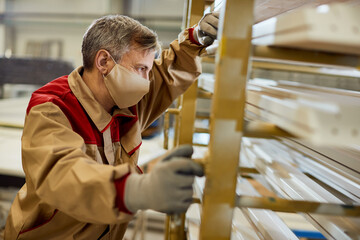Pensive carpenter wearing protective face mask while working in a workshop.