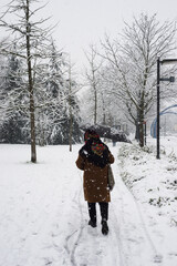 Fototapeta na wymiar Portrait on back view of woman walking in the street with a black umbrella by snowy day