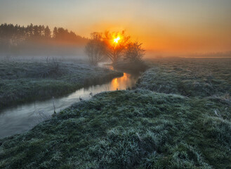 Beautiful spring sunrise over river banks. Morning fog