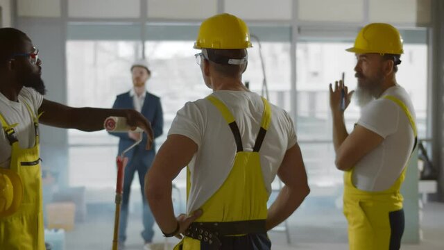 Back view of diverse team of builders listening to foreman at construction site