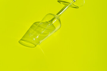 Champagne glass lies on lemon green surface. Glass with hard shadow 