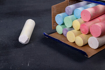 School chalk on a black blackboard. Accessories for lectures and lessons at school. Dark background.