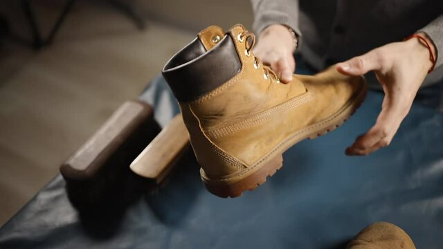 Male cobbler used yellow boots for cleaning and repairing