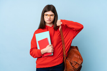 Young Ukrainian teenager student girl holding a salad over isolated blue background showing thumb down sign