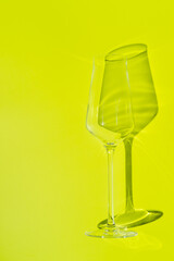 Champagne glass lies on lemon green surface. Glass with hard shadow 