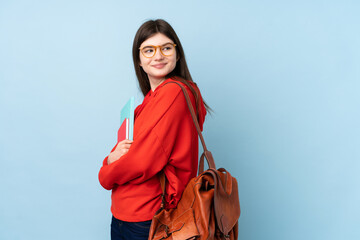 Young Ukrainian teenager student girl holding a salad over isolated blue background laughing