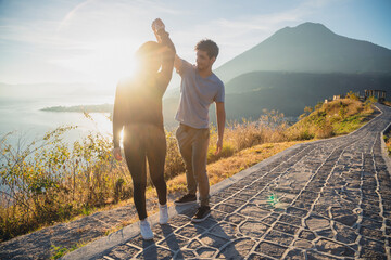 Young couple dancing overlooking Lake Atitlan at sunrise - traveling couple in love at the lake...