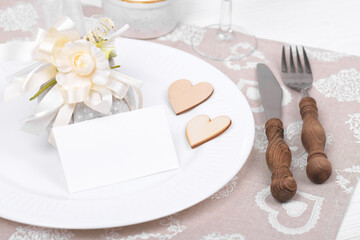 Romantic table setting with empty white card mockup and eco-friendly linen packaging gift with wooden heart decoration. Eco friendly zero waste present set for Valentines Day, Birthday or Mothers Day