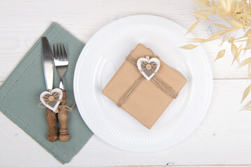Romantic table setting kraft paper gift with wooden heart decoration and dry plant. Eco friendly zero waste present set for Valentines Day, Birthday or Mothers Day, banner