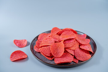 Red potato chips with salt on a gray background