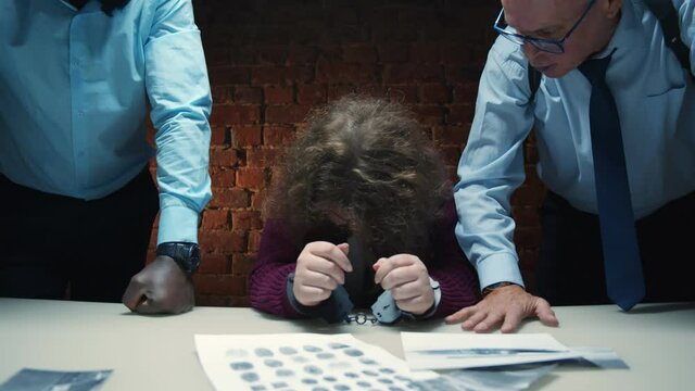 Aggressive police officers yelling at scared woman suspect during interrogation