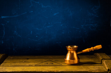 Obraz na płótnie Canvas Copper turk for making coffee. Turkish coffee. Blue background and wooden table.