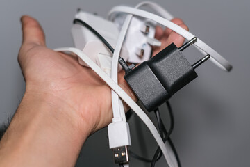 Man hand holding bunch of smartphone wired chargers,tech power devices tools