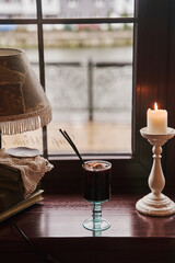 Traditional winter festive alcoholic drink. A glass of mulled wine is on the window.