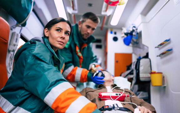 Doctors emergency or paramedics are working with a senior man patient while he lies on a stretcher in an ambulance.