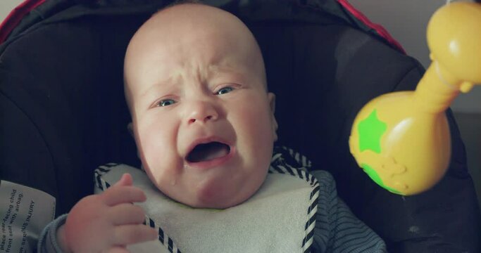 Portrait of funny, perplexed baby boy lying and crying at camera