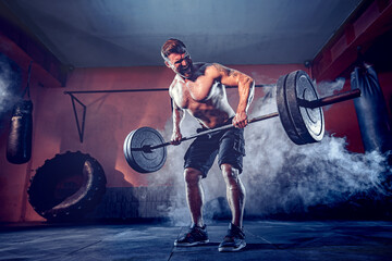 Muscular beardedman working out in gym doing exercises, strong male naked torso abs. Smoke on...