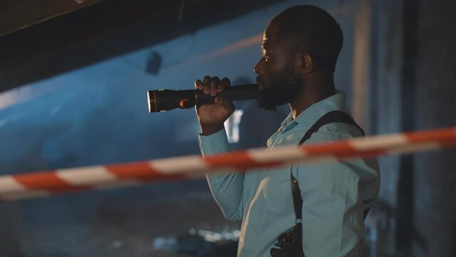 African investigator holding flashlight searching for evidence
