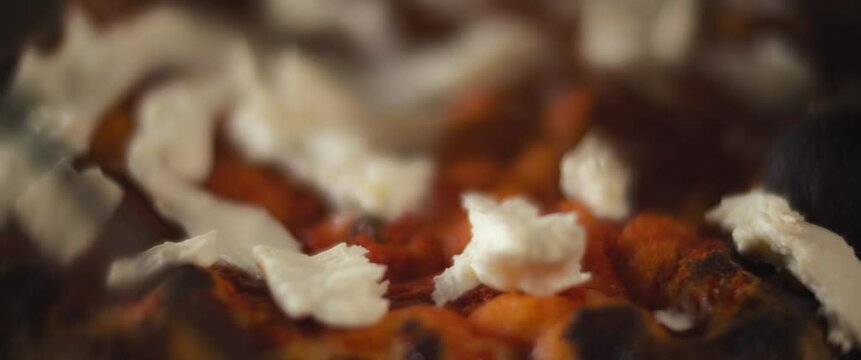 Close up of a chef spreading burrata cheese over a traditional al taglio pizza.