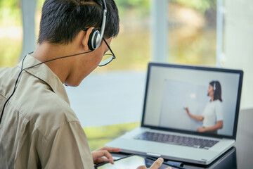Education learning online concept, Asian Teenage student wear headphone  using computer studying...