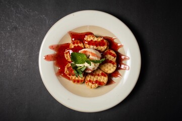 This is a waffle given strawberry sauce. A waffle is a dish made from leavened batter or dough that is cooked between two plates that are patterned to give a characteristic size, shape, and surface