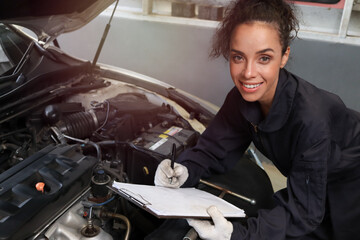 Fototapeta na wymiar Female auto mechanic working in garage, car service technician woman checking and repairing customer car at automobile service center, inspecting car vehicle under body and suspension system