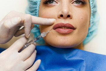 Lips augmentation injections for attractive girl. Plastic surgeon does injection in lip in medical...