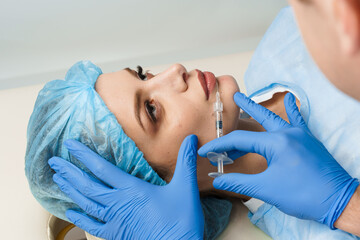 Lips augmentation injections for attractive girl on white background. Plastic surgeon does...