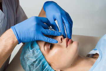 Lips augmentation injections for attractive girl on white background. Plastic surgeon does...