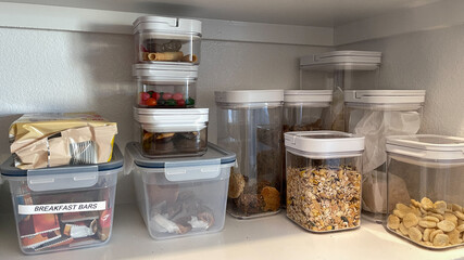 An organized pantry shelf with various types of cookies, cereal and snacks  and snacks