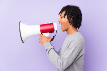 Young african american man isolated on purple background shouting through a megaphone