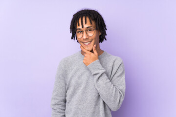 Young african american man isolated on purple background with glasses and smiling