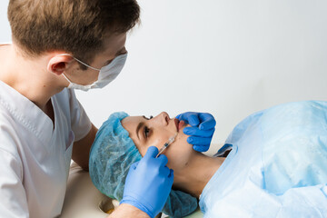 Lips augmentation injections for attractive girl on white background. Plastic surgeon does...