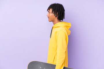 Young african american man isolated on purple background with a skate