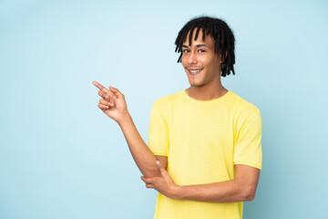 Young african american man isolated on blue background pointing finger to the side