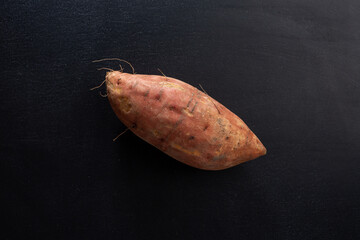 Raw sweet potato on dark background