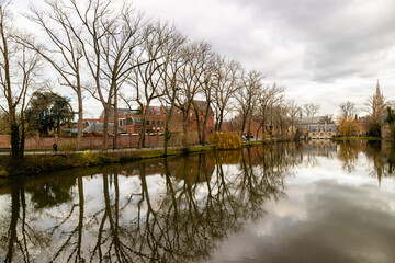 Árvores refletem na água de um canal na cidade de Bruges, Bélgica