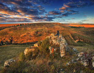 Woman on a hiking trip in the mountains walking on rocks. colorful autumn sunrise