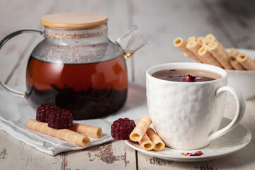 Herbal fruit tea with raspberry marmalade and wafer rolls, morning tea still life close up