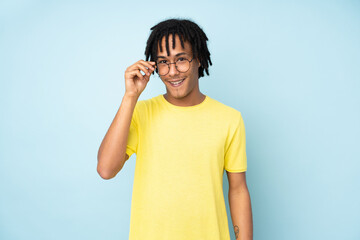 Young african american man isolated on blue background with glasses and surprised