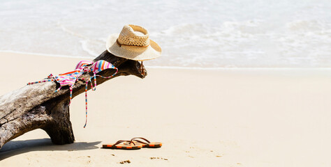 Summer vacations on sea shore. Swimming suit, hat, flip flops and on sand background on a tropical beach