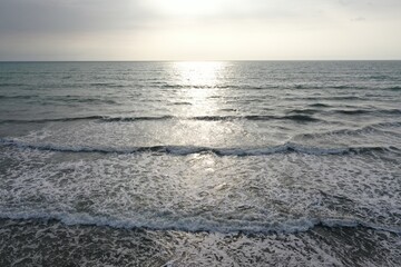 Aerial view, flying over the open ocean towards the sun at sunset